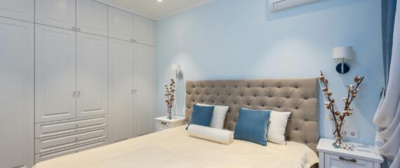 Comfortable bed and white big wardrobe in elegant bedroom