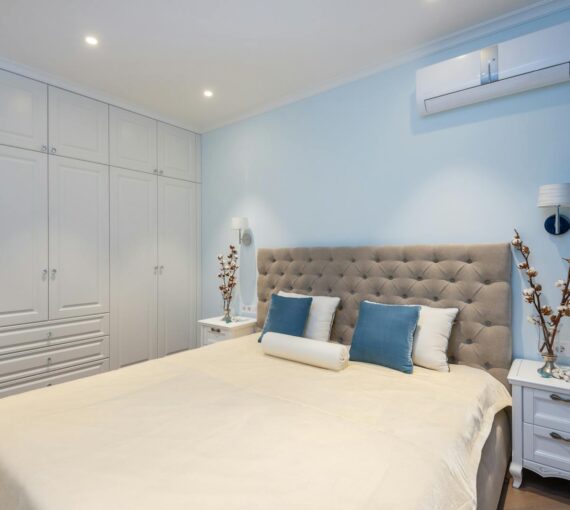 Comfortable bed and white big wardrobe in elegant bedroom